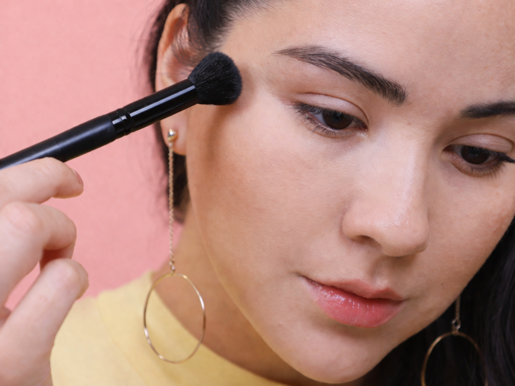 “using makeup brush to blend foundation evenly for smooth skin and prevent patchy makeup finish”