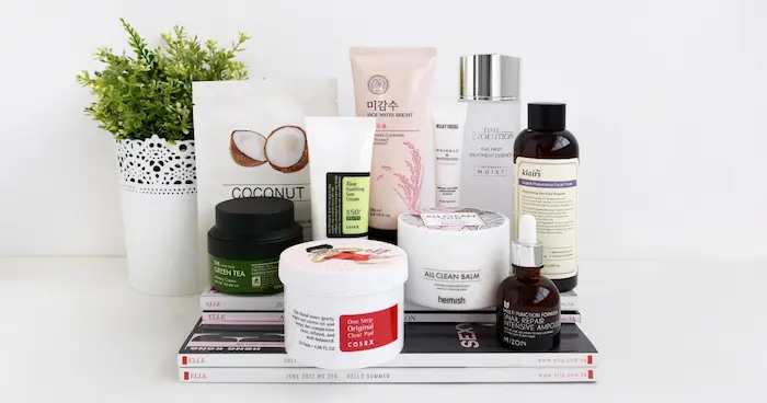 Korean skincare products flat lay with cleanser, toner, essence, serum and moisturizer for glass skin routine on white background